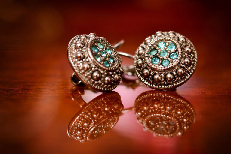 Silver earrings with green stones on a varnished wooden backgrou